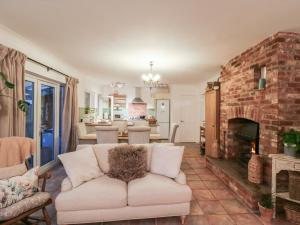een woonkamer met een bank en een stenen open haard bij Berkley Cottage in Coggeshall