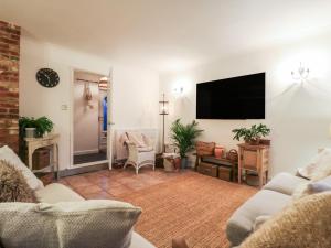 een woonkamer met een flatscreen-tv aan de muur bij Berkley Cottage in Coggeshall