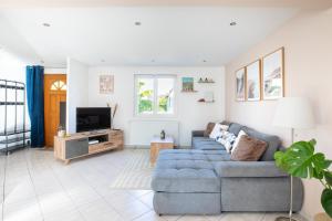 a living room with a blue couch and a tv at Maison confortable & familiale, proche Colmar et plus beaux coins d'Alsace in Muntzenheim