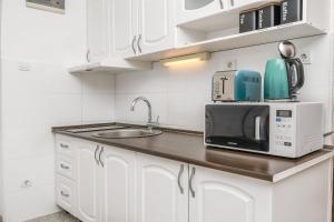 a white kitchen with a sink and a microwave at Apartments and Room Napoli in Bol