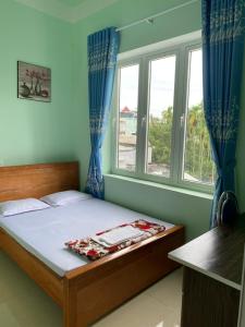a bedroom with a bed and two windows at MINH THU MOTEL in Quang Ngai