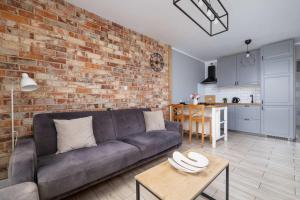 a living room with a couch and a brick wall at Modern 2-Bedroom Apartment with Remote Workspace in Katowice by Noclegi Renters in Katowice