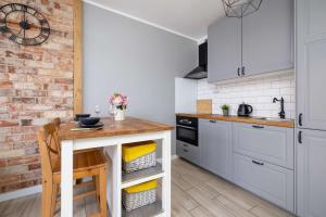 a kitchen with white cabinets and a wooden table at Modern 2-Bedroom Apartment with Remote Workspace in Katowice by Noclegi Renters in Katowice