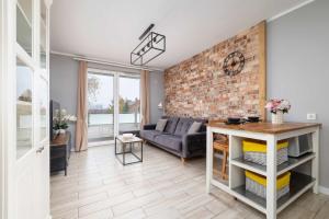 a living room with a couch and a brick wall at Modern 2-Bedroom Apartment with Remote Workspace in Katowice by Noclegi Renters in Katowice