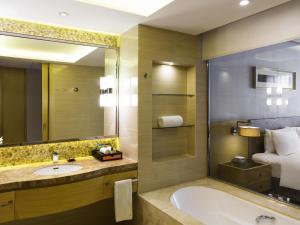 een badkamer met een bad, een wastafel en een bed bij Pullman Changshu Leeman in Changshu