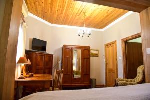 a bedroom with a bed and a desk and a tv at Hobbit Boutique Hotel in Bloemfontein