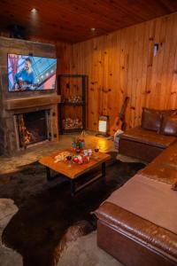 a living room with a couch and a tv and a fireplace at Cabana na Serra Lareira e Vista Deslumbrante in Rio Rufino