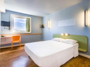 a bedroom with a large white bed and a window at ibis budget Sertaozinho in Sertãozinho