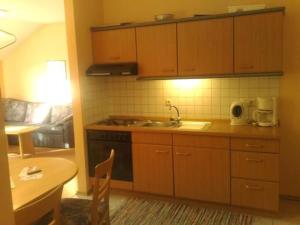 eine Küche mit Holzschränken, einer Spüle und einem Tisch in der Unterkunft Ferienresidenz Am weißen Regen mit kostenlosem w-lan und freien Eintritt ins AQACUR in Bad Koetzting + 19 Fotos