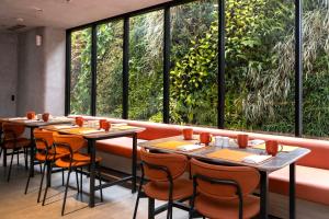 a row of tables in a restaurant with windows at TMG Hotel Tebet, Marclan Collection in Jakarta