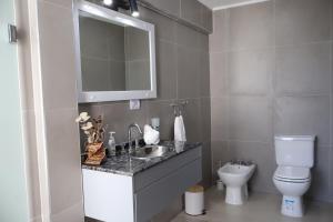 un bagno con lavandino, WC e specchio di Cabañas Casa Blanca a El Mollar