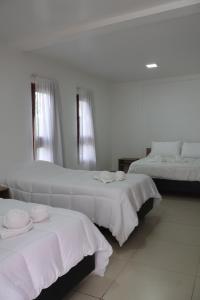 2 letti in una camera con pareti e finestre bianche di Cabañas Casa Blanca a El Mollar