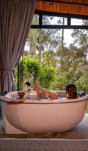 a woman laying in a bathtub in front of a window at Cabana na Serra Lareira e Vista Deslumbrante in Rio Rufino
