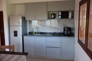 una cucina con mobili bianchi e un frigorifero bianco di Cabañas Casa Blanca a El Mollar Altre 13 foto