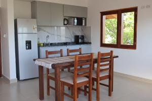 una cucina con tavolo, sedie e frigorifero di Cabañas Casa Blanca a El Mollar