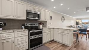 a kitchen with white cabinets and a black stove top oven at Lakeside Haven - Condo for 8 in Sunrise Beach +29 photos