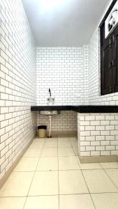 Un baño con lavabo y paredes de azulejos blancos. en Hotel Kundan Palace, en Nueva Delhi