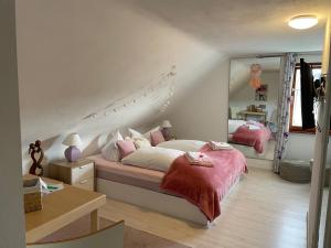 een slaapkamer met een bed met roze lakens en een spiegel bij Gästehaus Sandvoss in Titisee-Neustadt