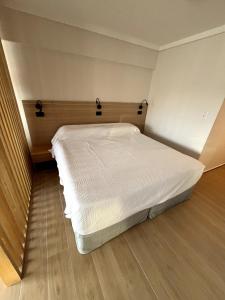 a white bed in a room with a wooden floor at Stuart's Apartment in Mar del Plata