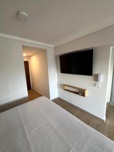 a bedroom with a large bed and a flat screen tv at Stuart's Apartment in Mar del Plata