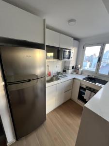 a stainless steel refrigerator in a kitchen with white cabinets at Stuart's Apartment in Mar del Plata