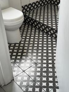 a bathroom with a toilet and a black and white tile floor at De Eike in Stellenbosch