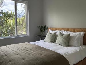 a bedroom with a bed with pillows and a window at De Eike in Stellenbosch