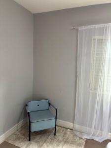 une chaise bleue dans une pièce avec une fenêtre dans l'établissement Suite familia - Centro de Itu, à Itu
