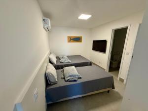 a bedroom with two beds and a tv at Peracanga Bacutia Guarapari Ls06 in Guarapari