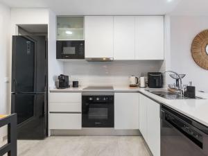 a kitchen with white cabinets and a black refrigerator at Apartment Aire Residencial by Interhome in Villacosta +16 photos