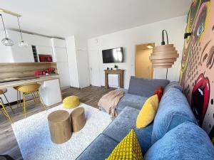 a living room with a blue couch and a kitchen at Mariani Place to Be in St Etienne in Saint-Étienne +1 photo