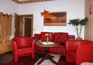 a living room with a red couch and two red chairs at Blick In Die Natur in Ilmenau +17 photos