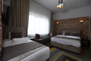 een hotelkamer met 2 bedden en een bakstenen muur bij Sur Central OTEL in Diyarbakır