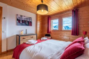 sypialnia z dużym białym łóżkiem z czerwonymi poduszkami w obiekcie Slow Chalet Tekoa 8 pers - 5 min from the slopes w mieście Manigod