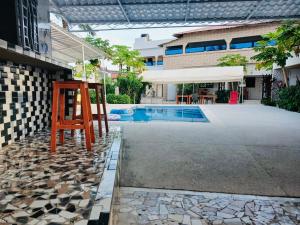 a pool with a wooden chair next to a building at La brise Du Cap in Cap Skirring