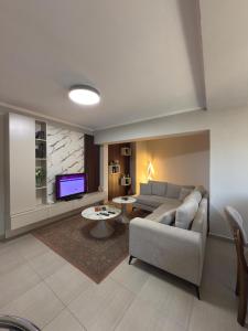 een woonkamer met een bank en een tv bij Hotel Bujtina Shqiptare in Tirana