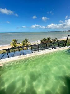 ein Swimmingpool mit Blick auf den Strand in der Unterkunft Melhores Flats - Seu desejo, pé na areia in Tambaú