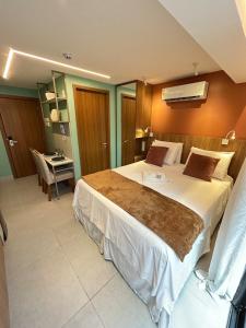 ein Schlafzimmer mit einem großen Bett und einem Schreibtisch in der Unterkunft Melhores Flats - Seu desejo, pé na areia in Tambaú