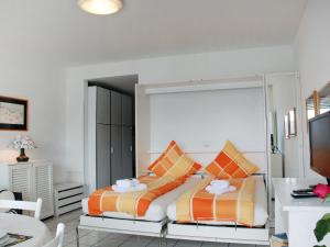 a bedroom with a bed with orange and white pillows at Studio Vista Lago by Interhome in Castagnola