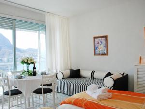 een witte kamer met een bed, een tafel en een bank bij Studio Vista Lago by Interhome in Ruvigliana