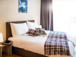 a bed with pillows and a blanket on it at Apartment Peaks Place Apartment-Hotel & Spa-3 by Interhome in Laax-Murschetg