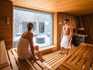 a man and a woman sitting in a sauna at Apartment Peaks Place Apartment-Hotel & Spa-3 by Interhome in Laax-Murschetg