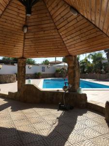 uma pérgola de madeira com uma piscina ao fundo em Villa Cirino Milone em Brucoli