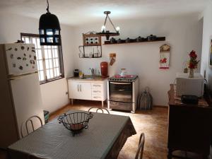 a kitchen with a table and a refrigerator at Mini Casarão in São Bento do Sapucaí
