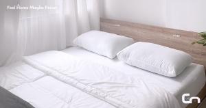 two pillows sitting on top of a white bed at Jarrdin Apartment by CozyNest Syariah in Bandung