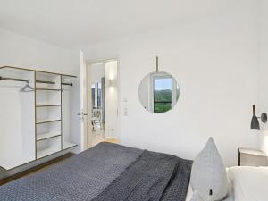 a white bedroom with a bed and a mirror at Apartment Penthouse Seeblick by Interhome in Lembruch