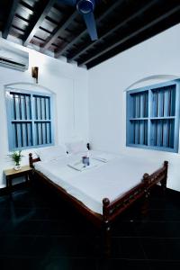 a white bed in a room with two windows at Idanazhi the corridor in Kozhikode