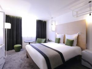 a hotel room with a large white bed with green pillows at Mercure Nancy Centre Gare in Nancy +79 photos
