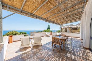 a patio with a table and chairs and the ocean at Villa fronte mare nel Salento in Castro di Lecce