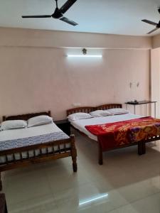 two beds in a room with a ceiling at Vidara Budget Stay in Trivandrum